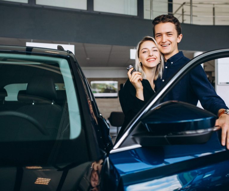 Photo of couple posing with car illustrates blog: "Collision Deductible Waiver vs Uninsured Motorist Property Damage: What Is the Difference?"