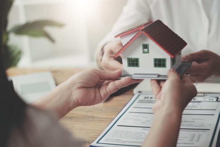 Photo of person holding small house model illustrates blog: "Homeowners Insurance: What Is Loss of Use Coverage?"