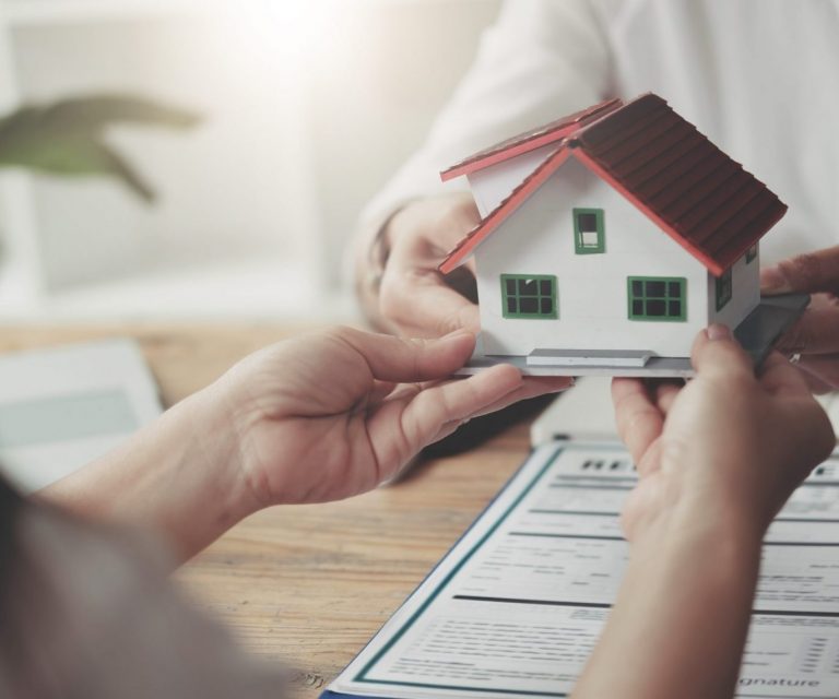 Photo of person holding small house model illustrates blog: "Homeowners Insurance: What Is Loss of Use Coverage?"