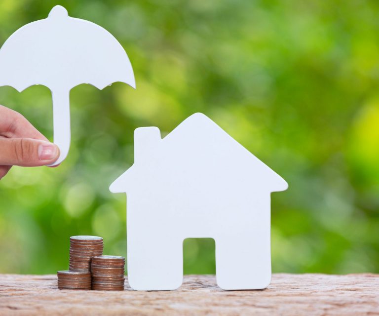 Photo of home cutout under cutout of umbrella illustrates blog: "What Does Homeowners Insurance Cover in California?"