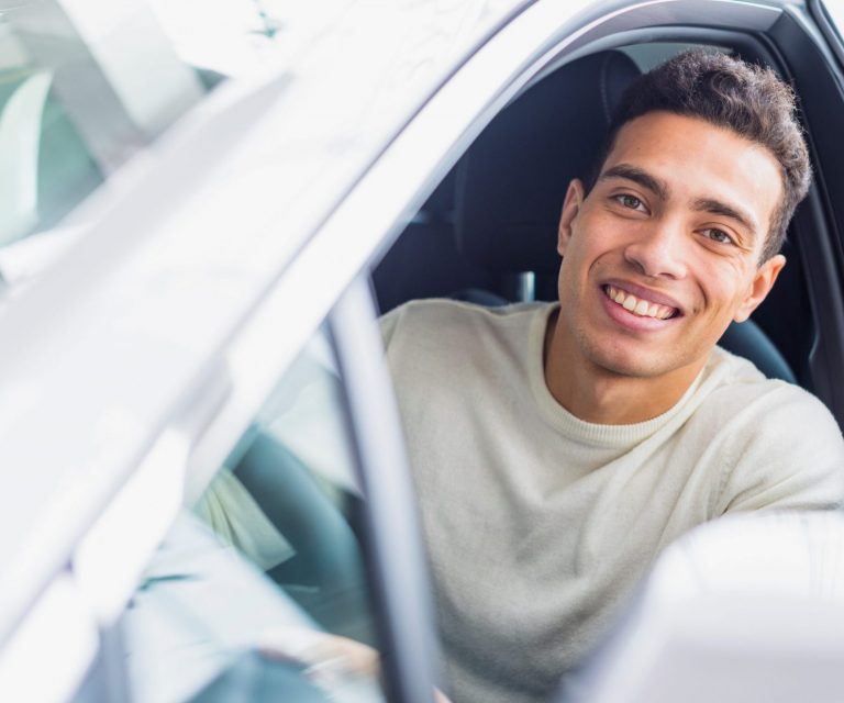 Smiling man in car illustrates blog "Will Auto Insurance Cover Paint Damage?"