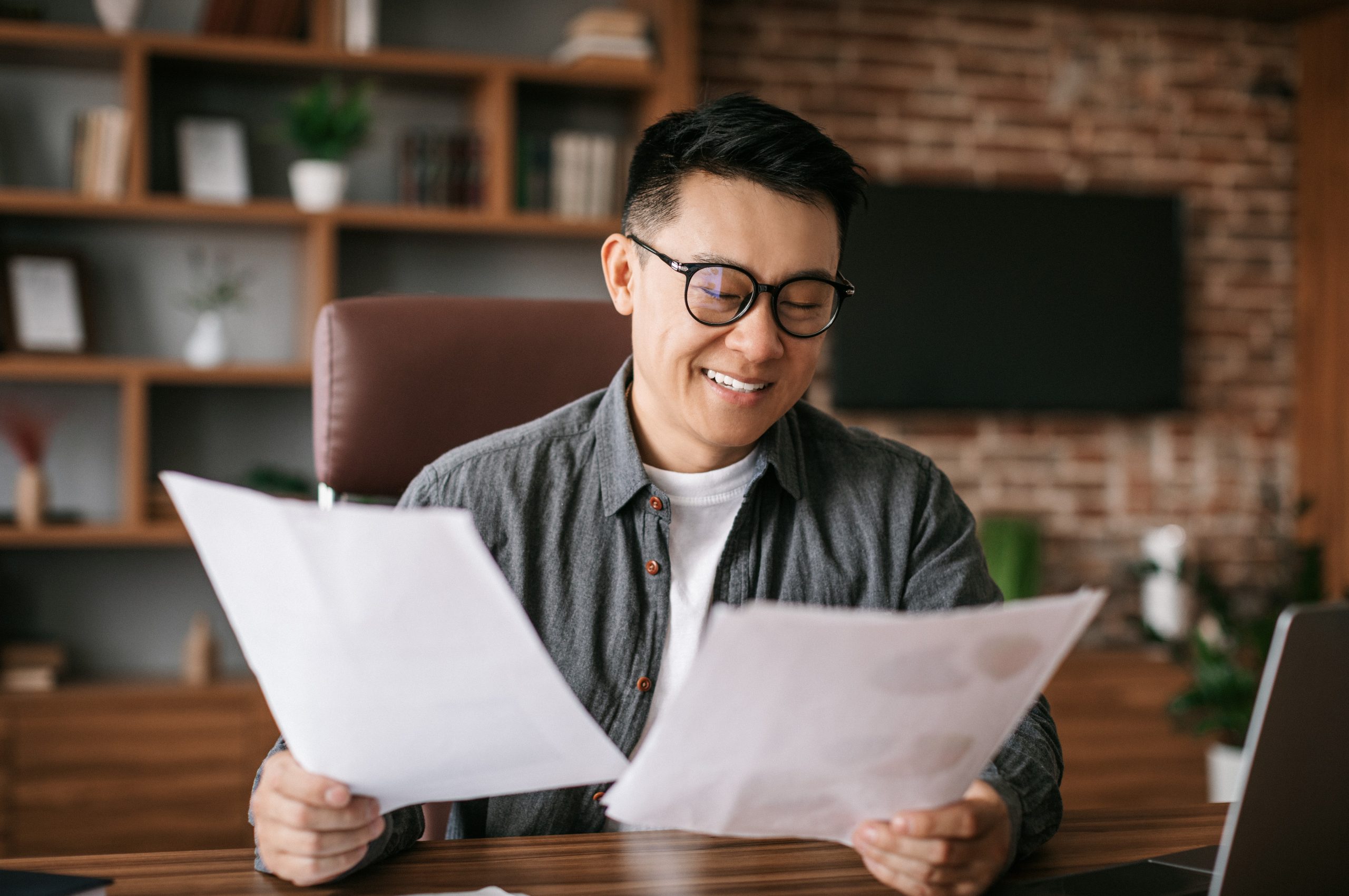 Photo of smiling man looking at documents illustrates blog: "Is Hazard Insurance the Same as Home Insurance?"