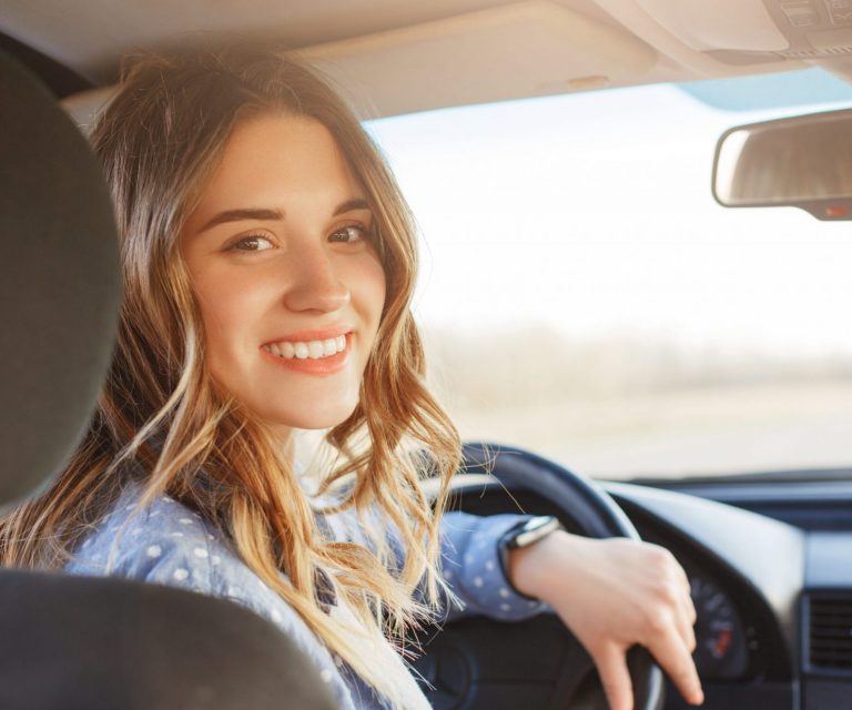 Photo of woman turning to look from the driver's seat of a car illustrates blog:; "Auto Insurance: What is Collision Deductible Waiver (CDW)?"