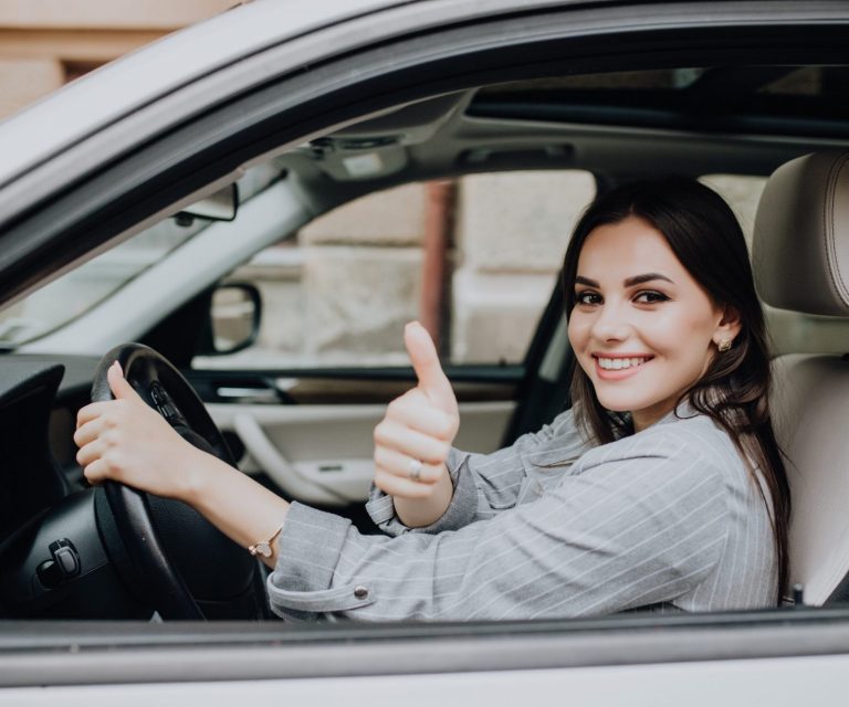 Photo of smiling woman in car giving thumbs up illustrates blog: "Auto Insurance: What Is Full Coverage Car Insurance in California?"