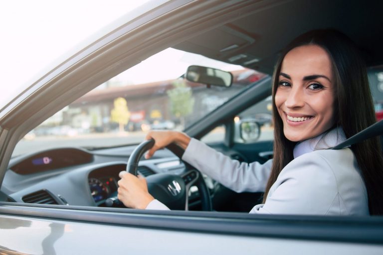 Woman in car holding steering wheel illustrates blog "What Auto Insurance Covers Theft?"