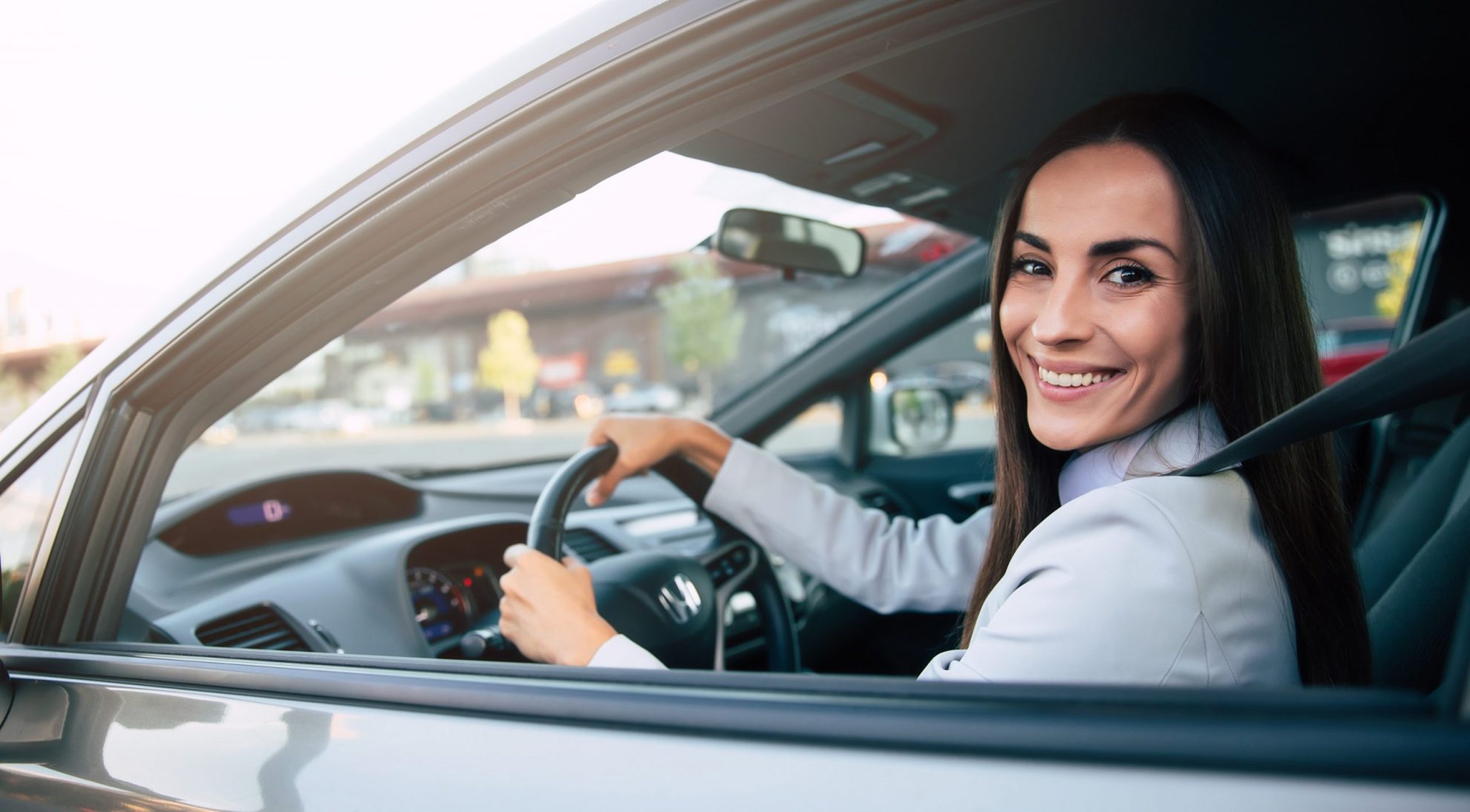 Woman in car holding steering wheel illustrates blog "What Auto Insurance Covers Theft?"