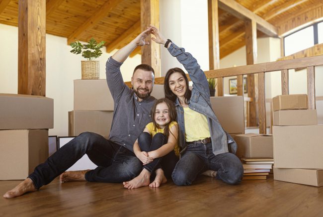 family-home-fp3 Family of mom, dad, and daughter sitting on the floor illustrate blog 'How Are Home Insurance Premiums Calculated?"