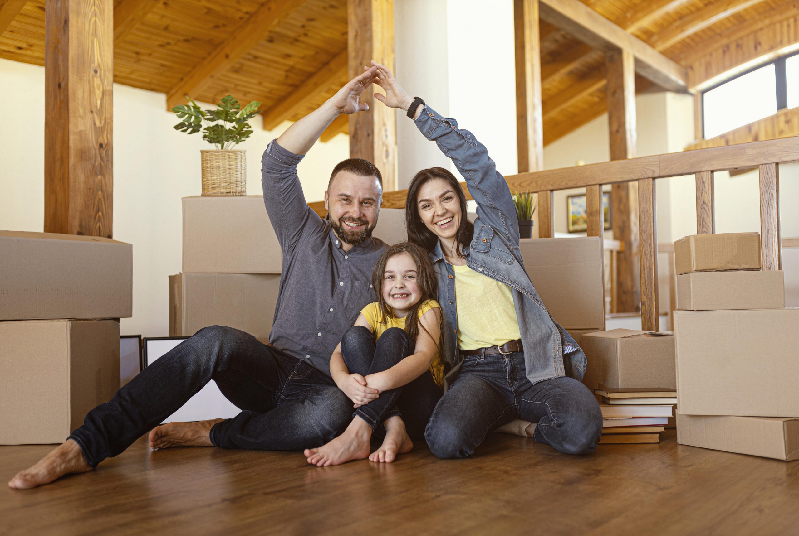 Family of mom, dad, and daughter sitting on the floor illustrate blog 'How Are Home Insurance Premiums Calculated?"