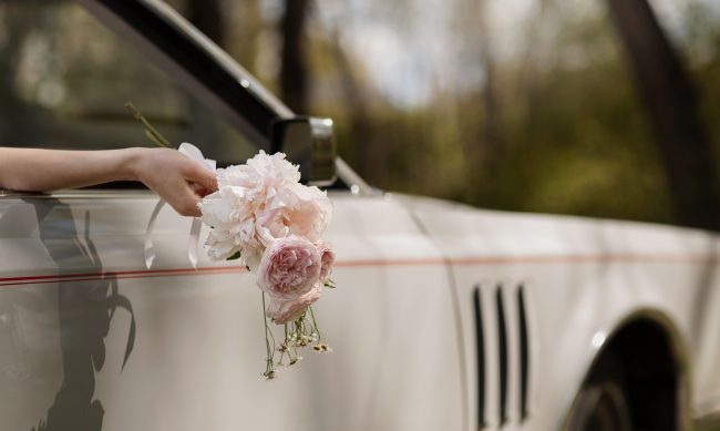 married-car-fp Hand of bride holding bouquet sticking out of a car window illustrates blog "Does Being Married Impact Your Auto Insurance Rates?"