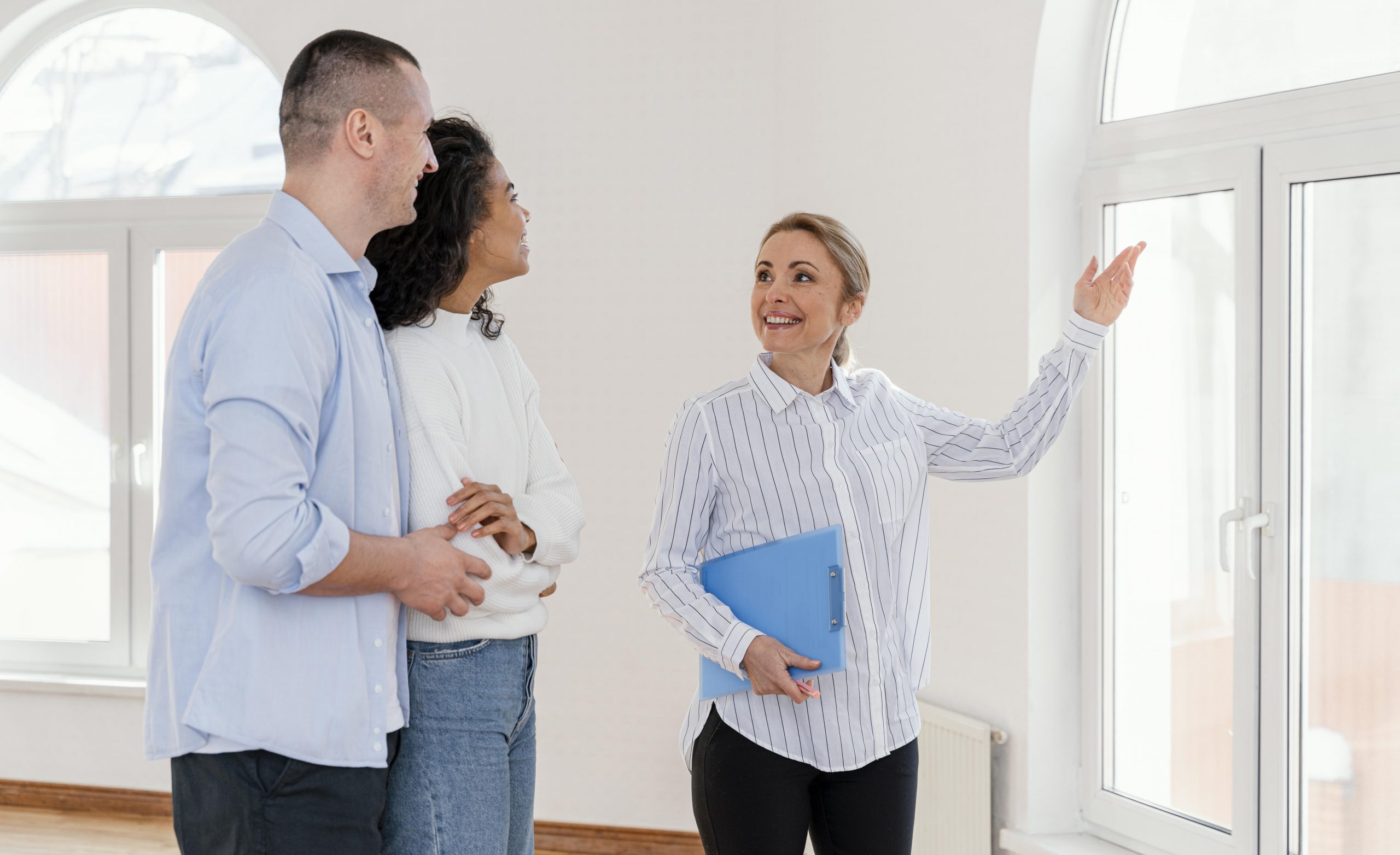 Woman showing home to couple illustrates blog "What Insurance Do I Need for an Investment Property?"